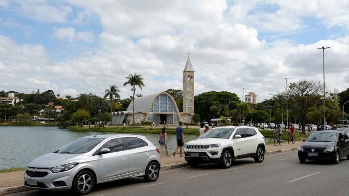 Carros trafegando na orla da Lagoa da Pampulha com a Igreja de São Francisco de Assis ao fundo, representando o cenário para a cotação de seguro auto em Belo Horizonte.